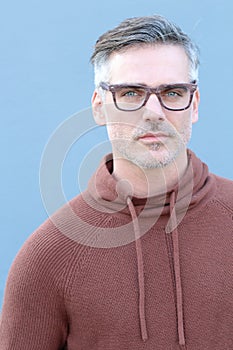 Close up Middle Age Man Wearing Brown Sweater and Eyeglasses Smiling at the Camera, on Blue Background