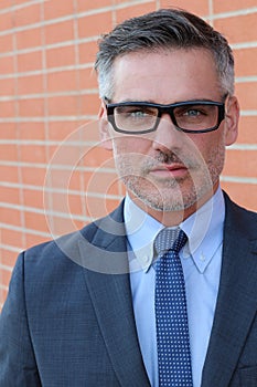 Close up Middle Age Man Wearing Business Suit and Eyeglasses Smiling at the Camera, Isolated on Brick Wall Background