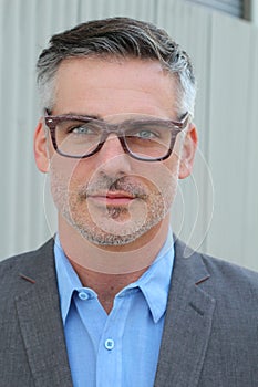 Close up Middle Age Man Wearing Business Suit and Eyeglasses Smiling at the Camera, Isolated on Gray Background