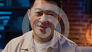 Close up middle-aged Asian man at night evening at home smiling at camera headshot Korean adult businessman at nighttime