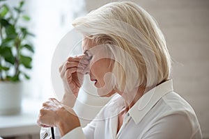 Closeup middle-aged woman taking off glasses reduces eye strain photo