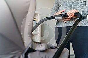 Close up on midsection of unknown caucasian pregnant woman holding her belly while checking baby carriage - motherhood and