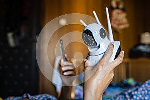 Close up on midsection of unknown woman holding home security surveillance camera and mobile phone trying to install an app while