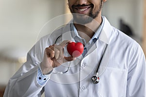 Close up millennial african doctor holding heart figure.