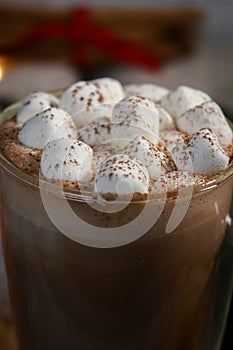 close up of mini marshmallows on hot chocolate in a glass mug, blurred lights background