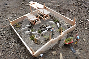 A close up of miniature figure of a goat herder feeding in a wooden cage.