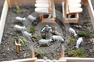 A close up of miniature figure of a goat herder feeding in a wooden cage.