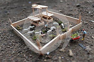 A close up of miniature figure of a goat herder feeding in a wooden cage.