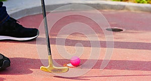 Close-up of a miniature golf putter and a pink golf ball