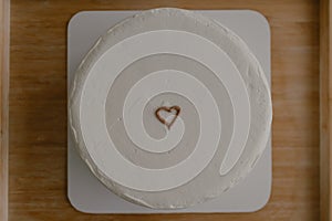 Close up of minimal white cake with tiny heart for birthday or Valentine on the bed.