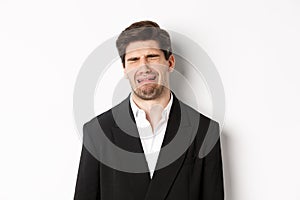 Close-up of miserable man in suit, crying and sobbing, feeling sad, standing against white background