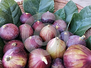 Close up mix figs fruit on figs leaves in bamboo basket,figs is healthy fduit and food ,fruit background