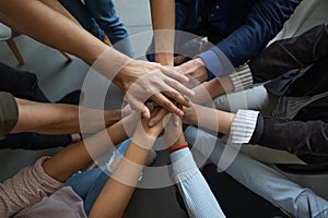 Close up mixed race business people putting hands together support.