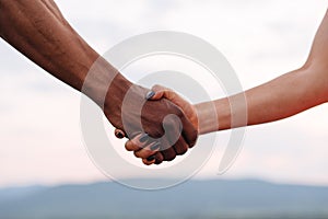 Close-up of mixed race couple holding hands on the misty mountain background. Symbolic photo