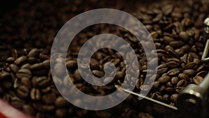 Close-up of mixing and stirred fragrant black coffee beans in roasting machine.