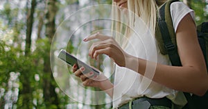 Close-up of a mobile phone in the hands of a female traveler walking through the forest. Social networks Navigator and