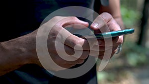 Close-up of a mobile phone in  hands male traveler walking forest. Using technology smartphone finding map pointing direction. Soc