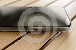 Close up of mobile phone wears white matte case left on wooden table.