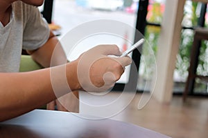 Close up mobile smart phone with blank screen on hands of unidentified people in coffee cafe.