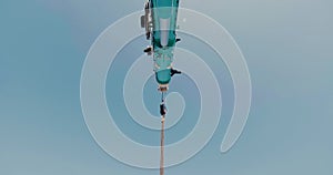 Close-up of mobile truck crane jib and boom on blue sky background.