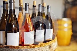 Close up of mockup of group of glass bottles with different wines and champagne on wooden wine barrel