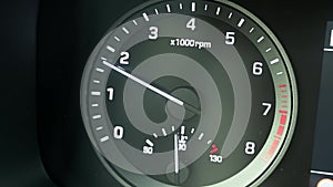 Close up of modern automotive tachometer on black background. The tachometer needle rises