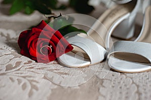 Close up of modern a beautiful, stylish wedding engagement ring, red roze and female shoes. photo