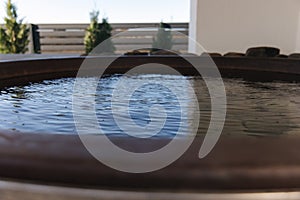 Close-up of modern big hot tub outdoor. Clear water in iron tube. Relaxation on holidays