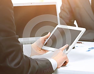 Close up of modern business-team using a tablet computer for work colleagues on the background