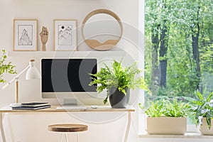 Close-up of a modern computer screen on a desk by the window in