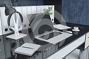 Close up of modern designer workplace with folders bookcase, empty laptop screen, coffee cup, decorative plant and other items.