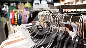 Close-up Modern fashionable women`s clothing hangs on black plastic hangers in a department store of a clothing store. Online