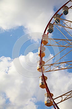 Close-up modern Ferris wheel against blue sky and white clouds, fun festival