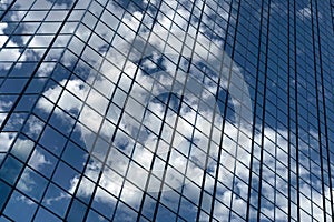 Close up of a modern glass office building. Reflection of the sky with clouds in the glass of the building