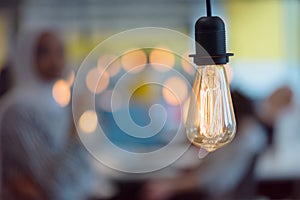 Close up of modern light bulb inside the modern interior of company in blur with employers