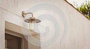 Modern metal hanging lamp in front of a window on a wall