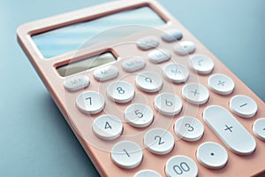 close up modern peach colour pastel calculator and white button on blue background