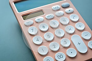 close up modern peach colour pastel calculator and white button on blue background, business and finance concept