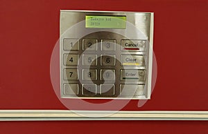 Close up of a modern security keypad on a red wall.