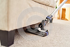 Close up of modern vacuum cleaner on beige carpet on floor in living room, copy space. Housework, household, spring-cleanig