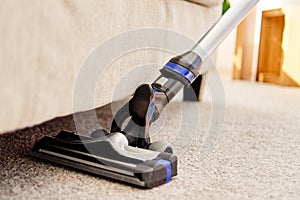 Close up of modern vacuum cleaner on beige carpet on floor in living room, copy space. Housework, household, spring-cleanig.