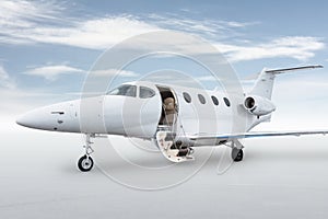 Close-up of the modern white private jet with an opened gangway door isolated on bright background with sky