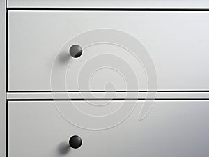 Close-up of a modern white wooden chest of drawers with black handles. Minimalism, modern interior