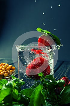 Close up. Mojito with strawberries and leafs of mint. Refreshing coolness of a lemonade. Blue background. Copy space