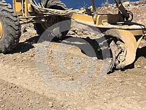 Close-up of moldboard planning road surface. Blade of motor grader during road construction works