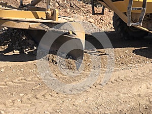 Close-up of moldboard planning road surface. Blade of motor grader during road construction works