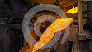 Close-up of molten metal flowing in factory. Stock footage. Beautiful molten substance flows down drain at steel plant