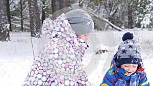 Close-up mom and baby play in a winter park or forest, throwing snow and experiencing emotions of happiness, pleasure