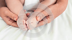 Close up mom hands holding foots baby in a room with a lot of sunlight. Newborn