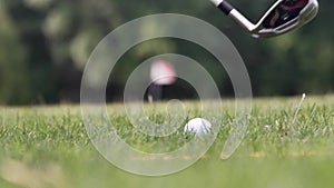 Close up of a moment when ball being hitted by a wedge on the green golf pitch on a sunny summer day rising grass up. Outside. slo